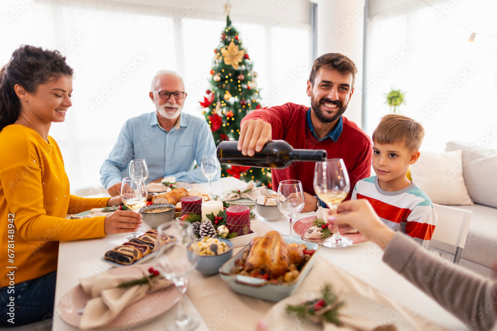 Family pouring wine and making a toast while having Christmas dinner at home Family pouring wine and making a toast while having Christmas dinner at home