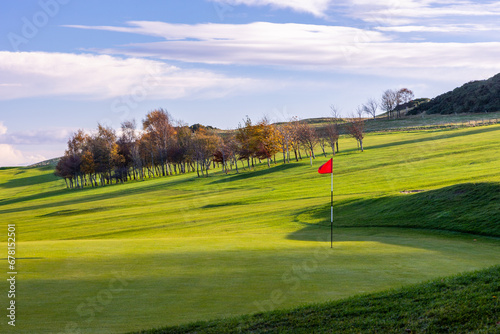 Bright green with red flag in the hole at a golfcourse in Scotland in autumn