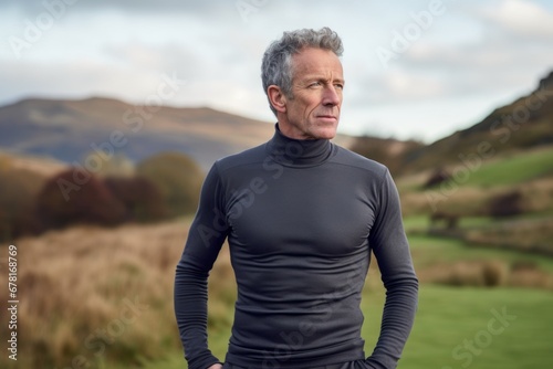 Portrait of a blissful man in his 50s showing off a lightweight base layer against a quiet countryside landscape. AI Generation