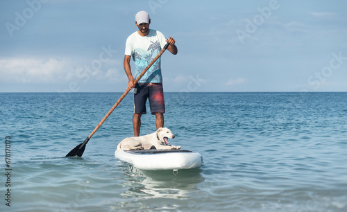 a guy on a sup board with a paddle with a dog stands on the sea in summer, Stand Up Paddle