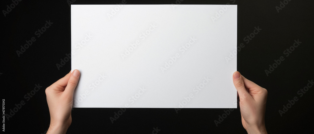 Hands holding a blank paper sheet on a black background. Mock up. Hands holding a blank paper sheet on a black background. Mock up.