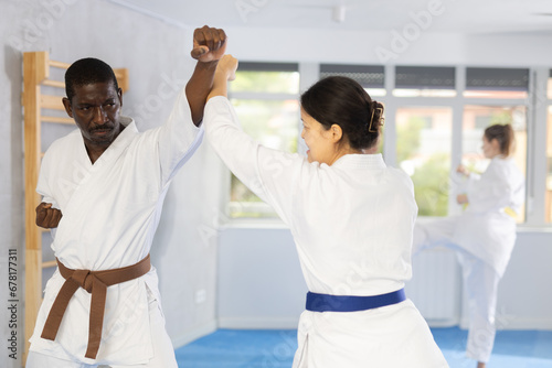 Active middle-aged man attendee of karate classes practicing fighting techniques during workout session