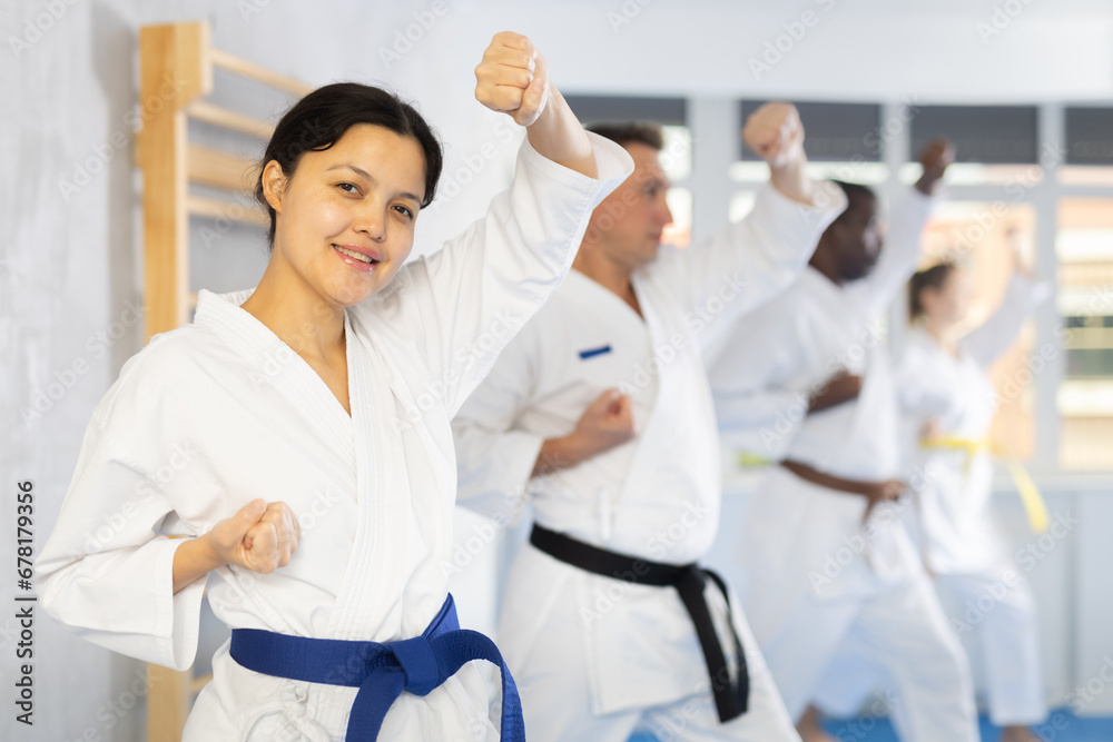 Obraz premium Group of multinational athletic people in kimonos try new fighting techniques at karate lessons