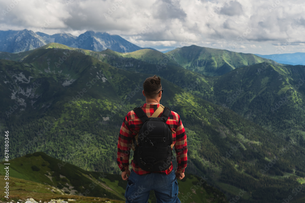 Male traveler with a briefcase in the Polish Tatras, view from the back.
