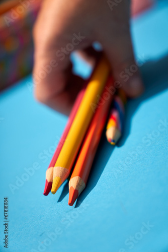 Colorful pencils and crayons holding in hand on a blue background 