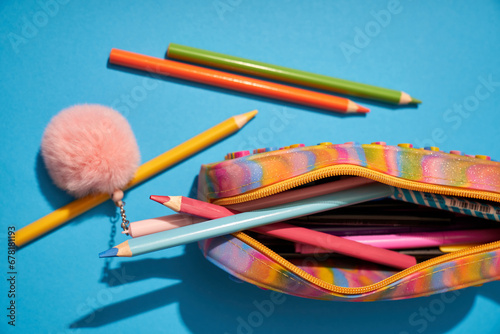 Colorful pencil case with crayons on a blue background top view