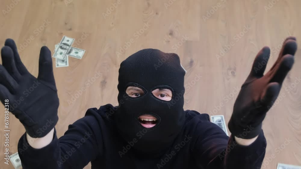 A robber in a black mask takes money from a safe. Danger of robbery