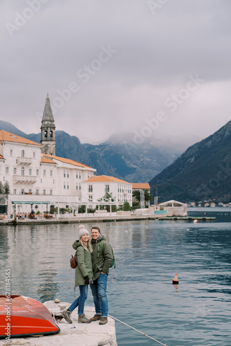 Man and woman are hugging on the Perast embankment in winter. Montenegro