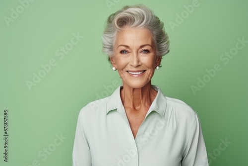 Portrait of a blissful woman in her 70s wearing a classic white shirt against a pastel green background. AI Generation