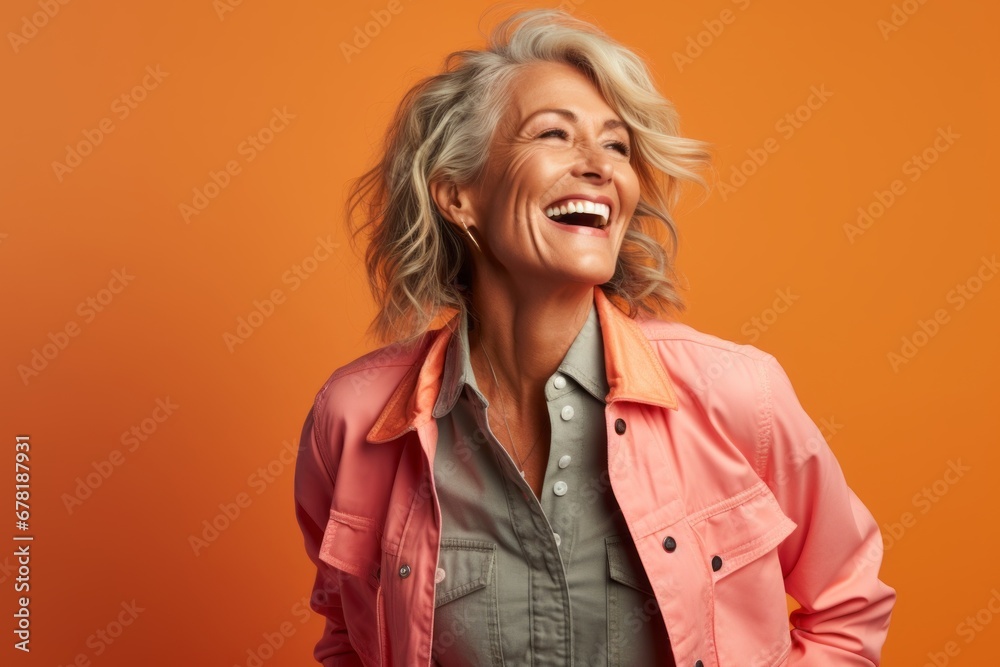 Portrait of a joyful woman in her 50s sporting a stylish varsity jacket against a pastel orange background. AI Generation Portrait of a joyful woman in her 50s sporting a stylish varsity jacket against a pastel orange background. AI Generation