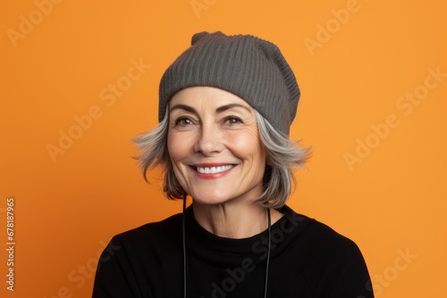Portrait of a happy woman in her 50s sporting a trendy beanie against a pastel orange background. AI Generation © CogniLens