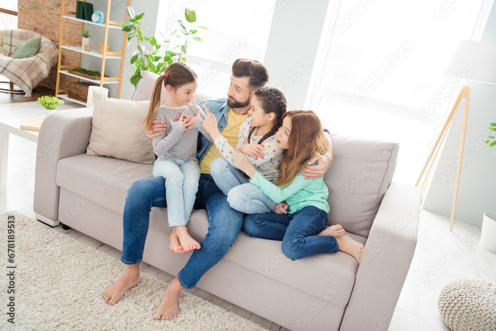 Fototapeta premium Portrait of four persons sit on sofa handsome guy cuddle girls point finger funny sister spend weekend home indoors