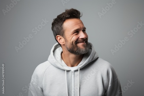 Portrait of a blissful man in his 40s sporting a comfortable hoodie against a soft gray background. AI Generation