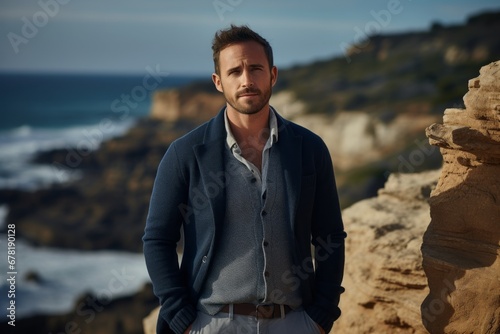 Portrait of a satisfied man in his 30s wearing a chic cardigan against a rocky cliff background. AI Generation