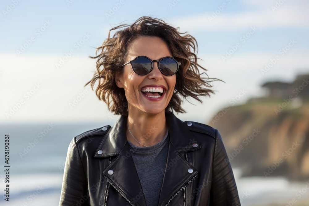 Portrait of a smiling woman in her 40s sporting a stylish leather blazer against a serene seaside background. AI Generation Portrait of a smiling woman in her 40s sporting a stylish leather blazer against a serene seaside background. AI Generation