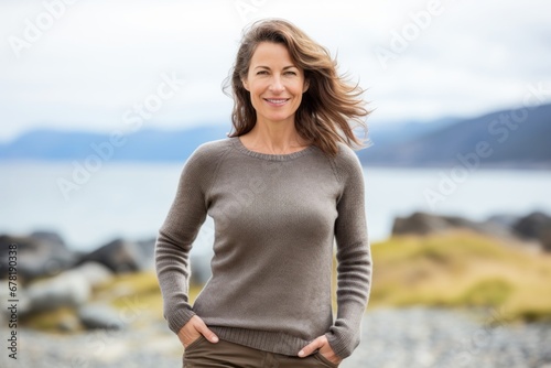 Portrait of a merry woman in her 40s showing off a thermal merino wool top against a serene seaside background. AI Generation