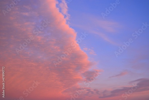 Dramatic sky with pink clouds illuminated by the setting sun against a blue backdrop