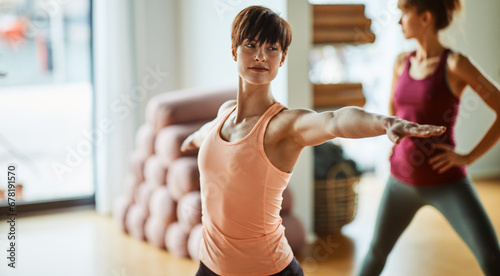 Young woman doing the warrior pose in yoga class photo