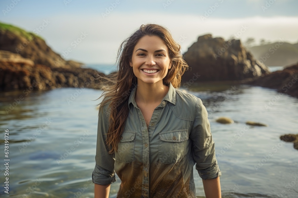 Portrait of a grinning woman in her 30s sporting a vented fishing shirt against a peaceful tide pool background. AI Generation