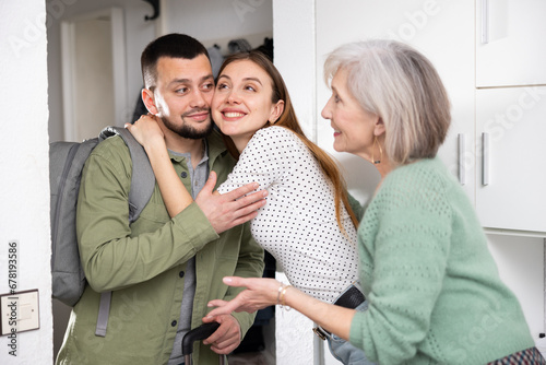 Man came home after work trip, his wife and mother-in-law welcoming and embracing him at home.