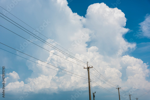 View of utility poles with blue sky and white clouds as a background.