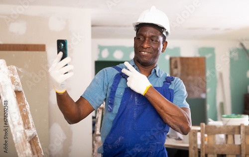 Positive african american contractor working on an construction site indoors takes a selfie during a work break