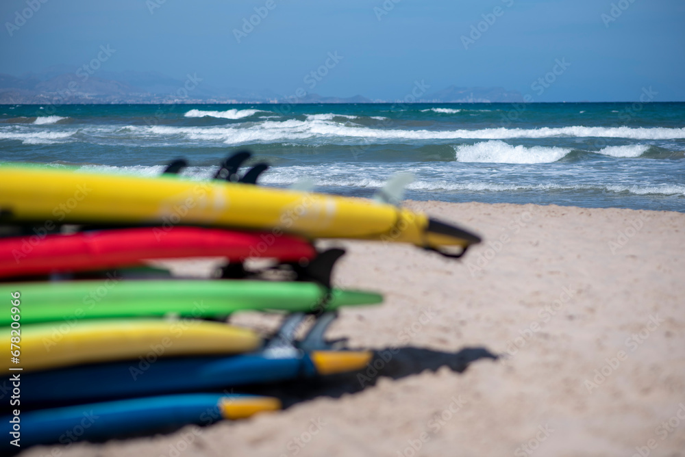 Set of different color surf boards in a sandy. Surf boards for rent on sandy beach. Soft toned photo.