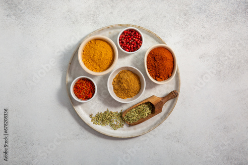 Assorted colorful spices in small bowls on tray on gray background. Food background. Top view, copy space.