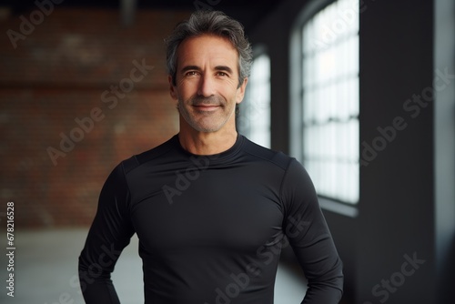 Portrait of a smiling man in his 50s showing off a lightweight base layer against a empty modern loft background. AI Generation
