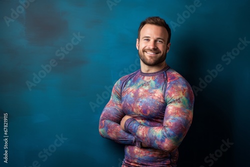 Portrait of a smiling man in his 30s showing off a vibrant rash guard against a plain cyclorama studio wall. AI Generation