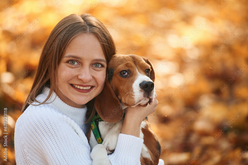 Close up portrait, embracing animal. Woman is with her cute dog in the autumn forest