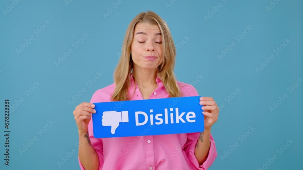Young woman blogger holds blue sign of Dislike button Young woman blogger holds blue sign of Dislike button