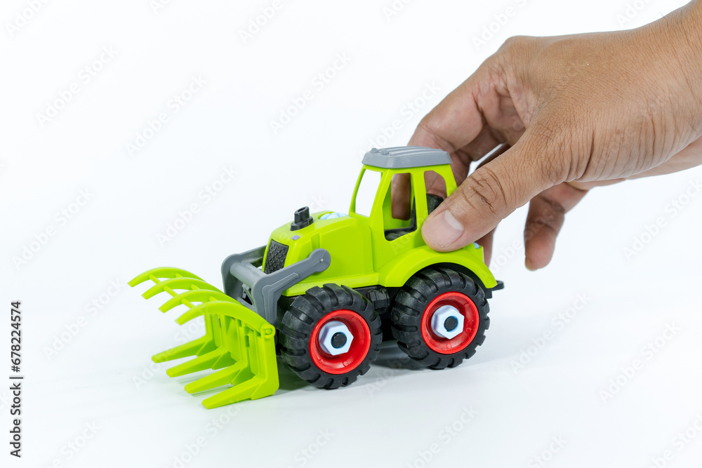 hand man playing with the car close on a white background. Plastic child toy on white backdrop. Construction vehicle. Children's toy. Tractor Toy. hand man playing with the car close on a white background. Plastic child toy on white backdrop. Construction vehicle. Children's toy. Tractor Toy.