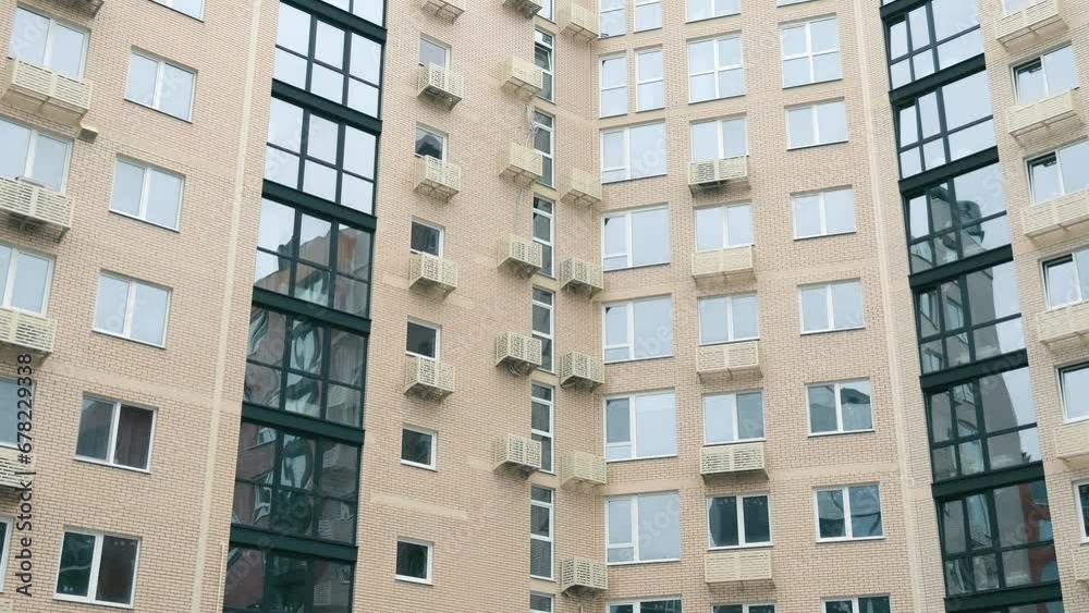 Front view of a recently built modern multi-story residential building. Exterior of a newly built modern residential building with baskets for air conditioners on the facade.