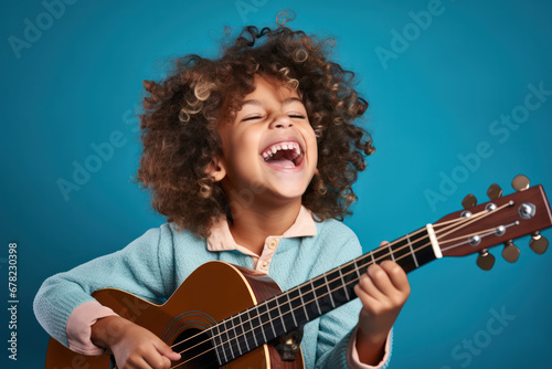 Musical Delight, Happy Child Strumming a Guitar with Joy on Blue Background