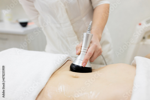 RF body cavitation lifting procedure in a beauty salon. Ultrasound therapy to reduce fat and elasticity of the skin. Cosmetic ultrasonic anti-cellulite massage close-up photo
