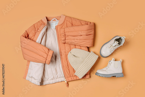 Stylish terracotta children's autumn jacket, knitted hat and boots. Fashion kids outfit for for spring, autumn or winter. Flat lay, top view photo