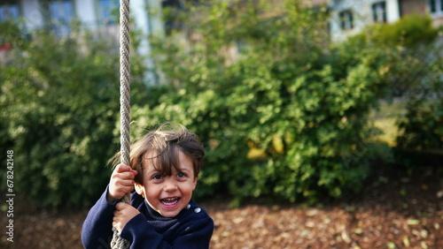 Excited Child Enjoying Rope Slide Amidst Fall Foliage, Joyful Caucasian Child Sliding Down Rope Between Trees in Autumn