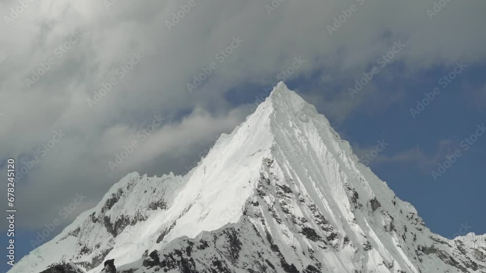 ice covered glacier of a pyramid shaped mountain at laguna paron lagoon in the high andes mountains of the cordillera blanca at huascaran, Peru, with snow covered mountain peaks on a bright sunny day.