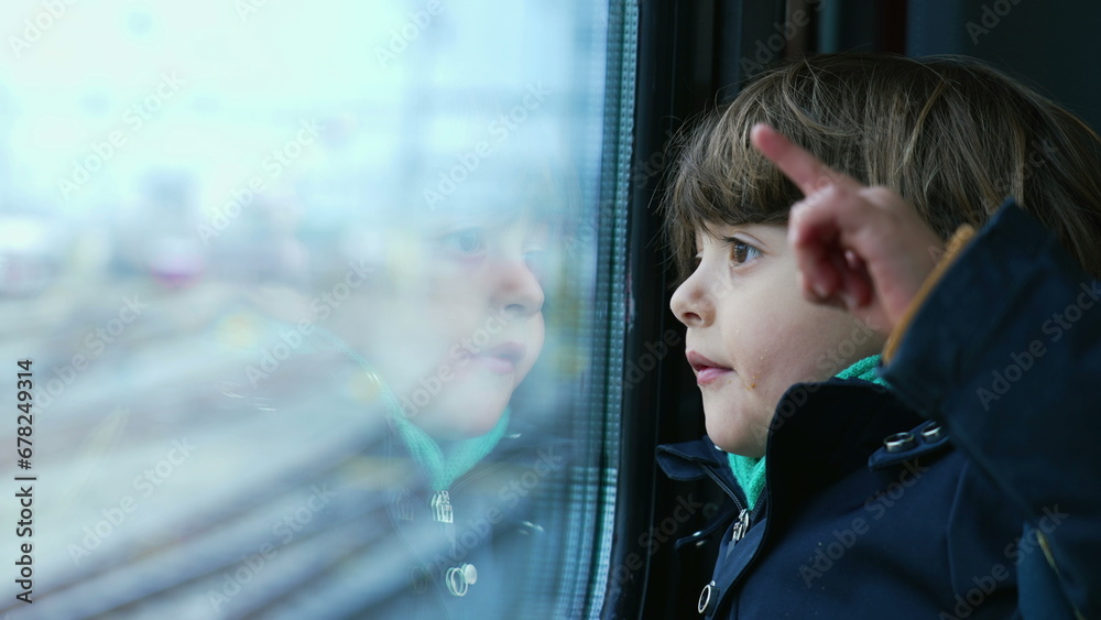 Small boy passenger staring at landscape passing by from trian window. Kid wearing scarf and jacket during autumn fall season travel Small boy passenger staring at landscape passing by from trian window. Kid wearing scarf and jacket during autumn fall season travel