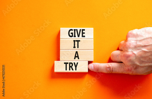 Give it a try symbol. Concept word Give it a try on beautiful wooden block. Beautiful orange table orange background. Businessman hand. Business give it a try concept. Copy space.