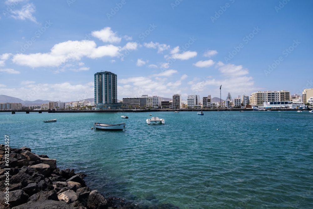 View of the city of Arrecife from the Fermina islet. Turquoise blue water. Sky with big white clouds. Seascape. Lanzarote, Canary Islands, Spain.