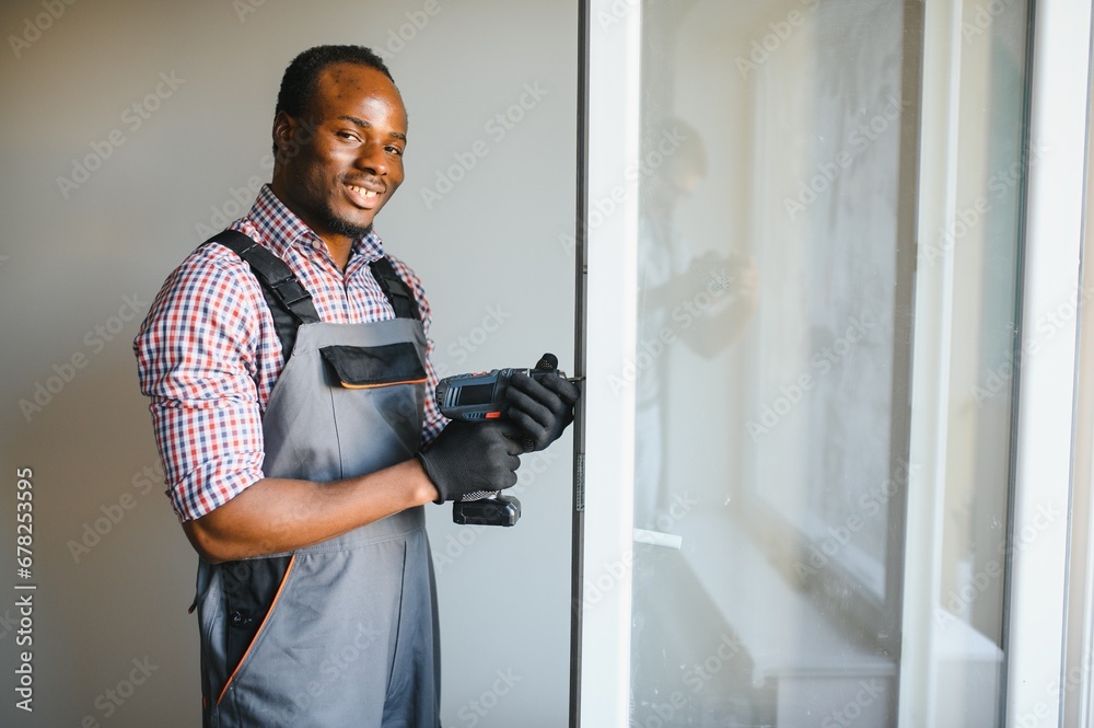 Close-up Of Young African Handyman In Uniform Installing Window