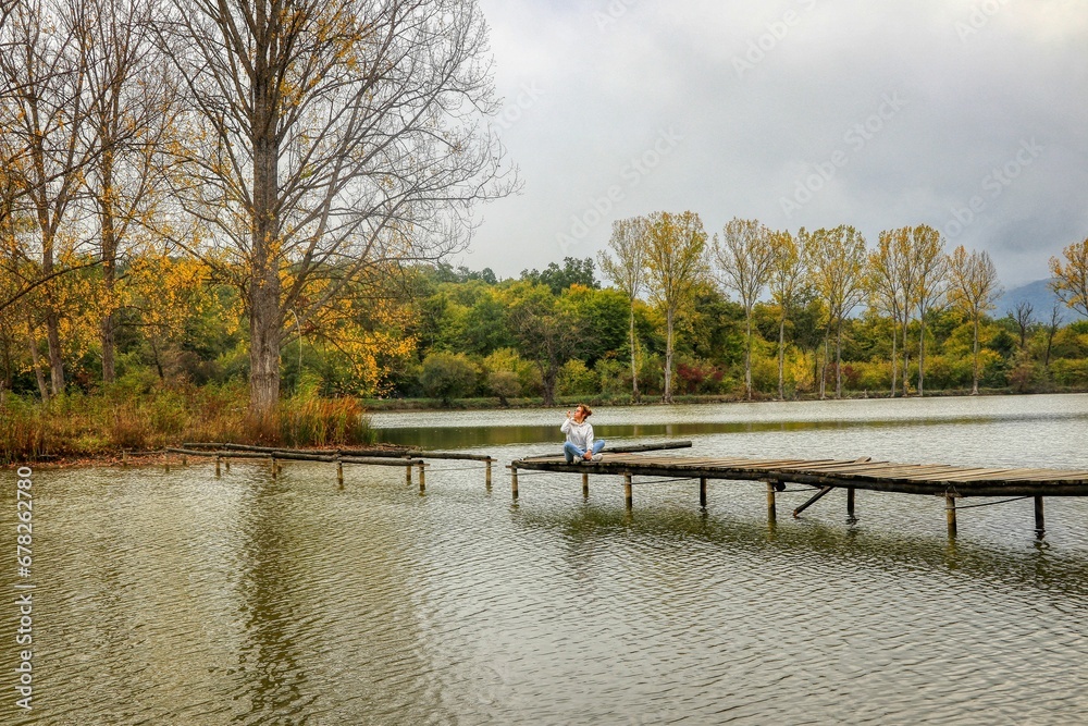 Female on a pier in a lake in a park