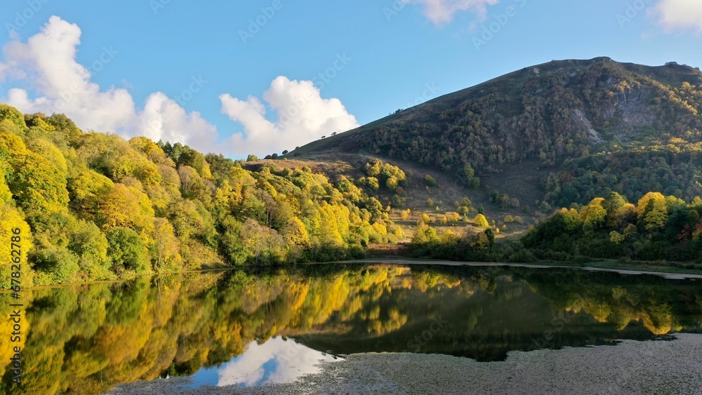 Mountainous lake with reflections of trees and clouds