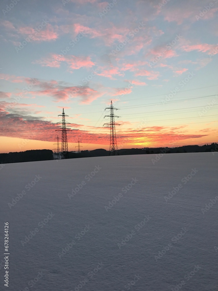 Vertical shot of Power transmission systems during the winter with sunset view in the background