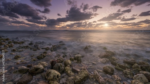 a large amount of rocky ground next to the ocean at sunset