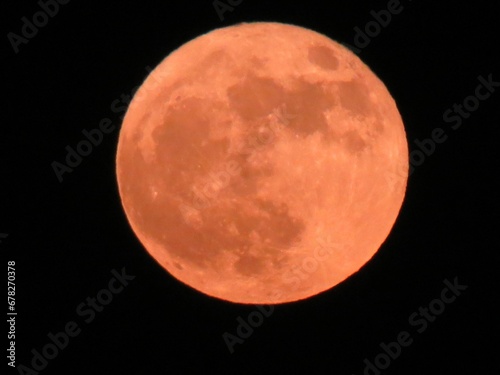 Closeup shot of a beautiful bright orange full moon in a black sky photo