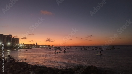 Beachfront twilight in Fortaleza  city lights and azure waves under a soft pink sky