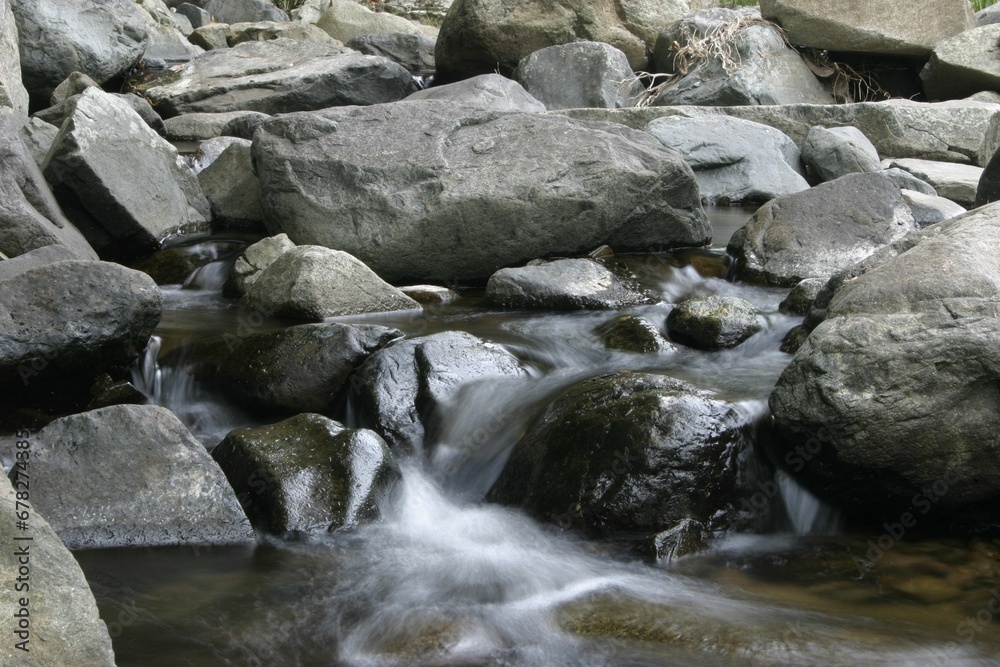 Gray rocks with the water flowing over them in a park Gray rocks with the water flowing over them in a park